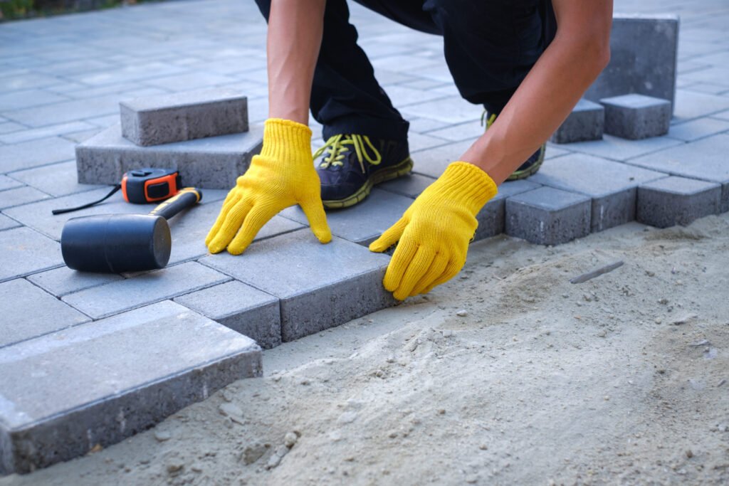 Paving 2 Person paving with yellow gloves and tools scaled 1